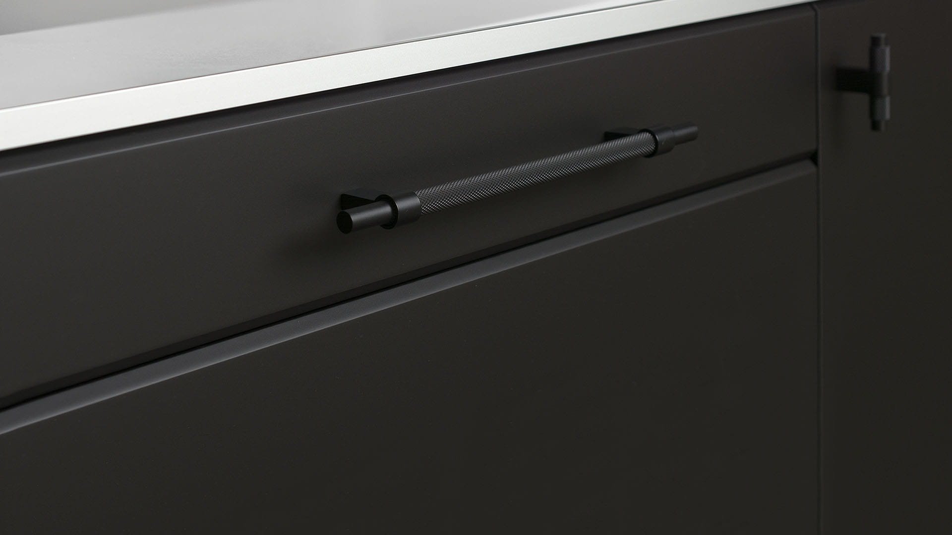 Zdjęcie przedstawia uchwyt meblowy podłużny z serii Pitch na meblu od Beslag Design